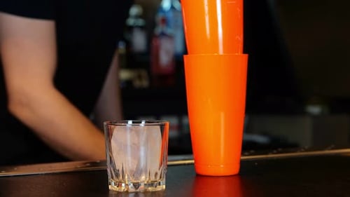 Male Bartender Working in a Bar While Making Cocktail Bartender Putting a Piece of Ice Into a Glass