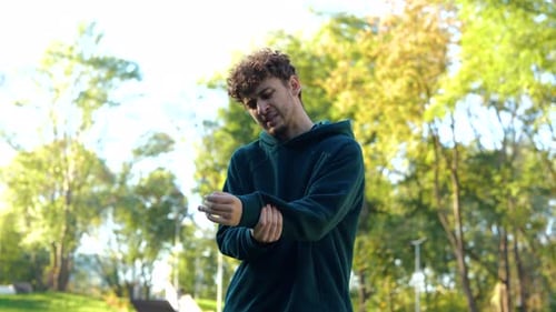 Un sportif qui court dans un parc se sent blessé au bras après l'entraînement Jeune homme caucasien debout dehors