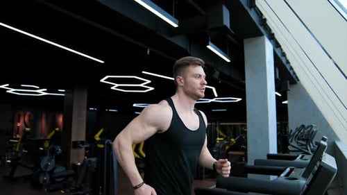 Homem bonito com corpo treinado está correndo em uma esteira.