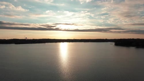sunset reflecting off a large lake with calm water, aerial drone