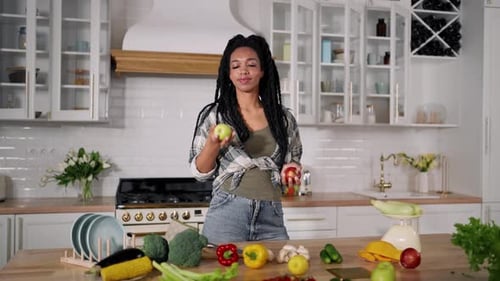 Young Woman Juggling Apples in Bright Kitchen