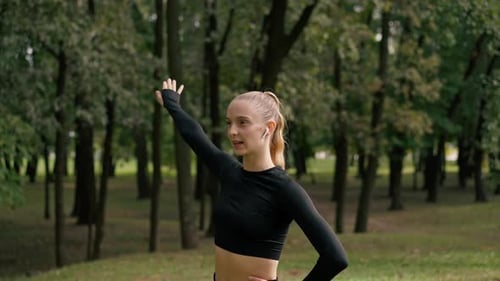 portrait of a young beautiful girl in sportswear in a city park doing stretching exercises