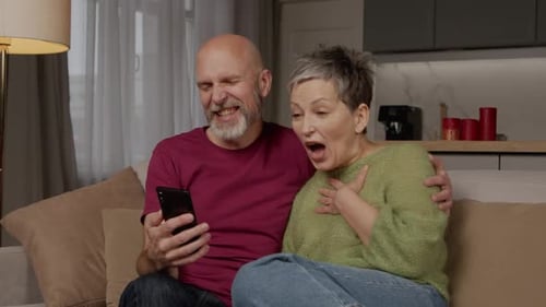 Mature Couple Laughs Together While Looking at Phone