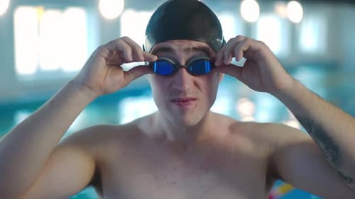 Zoom in Portrait of Confident Smiling Man in Cap Putting on Swimming Goggles Looking at Camera