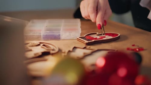 Handgefertigte Weihnachtsdekoration, detailgetreue Kreation von Weihnachtsschmuck mit Perlen, Person