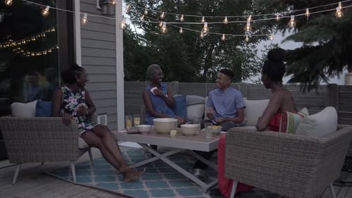 Friends Play Cards on Patio Under String Lights