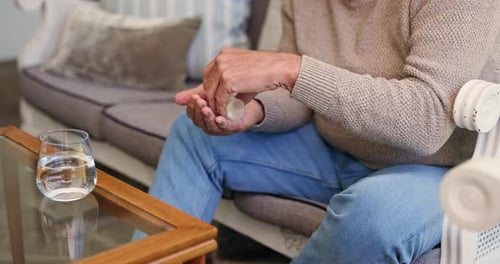 Senior Man Taking Pills with Water Inside Home
