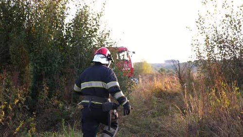 Firefighter Walking in a Rural Field Near Firetruck