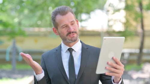 Man in Suit Video Conferencing on Tablet Outdoors