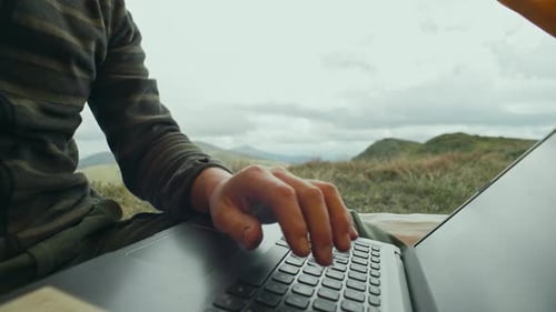 Abrindo um laptop para trabalhar ao ar livre nas montanhas