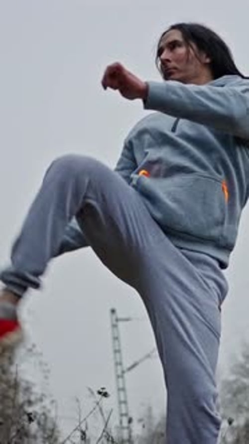 Man Practicing Kicks in Overcast Urban Environment