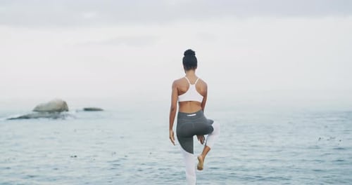 4k video footage of an unrecognizable woman practicing yoga at the beach