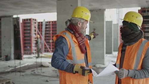 Co-workers Discussing Building Plan at Construction Site