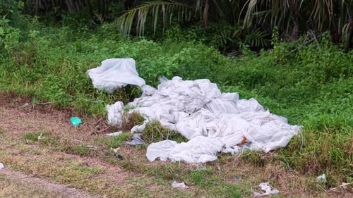 Aerial view of discarded white fabric and litter in grass