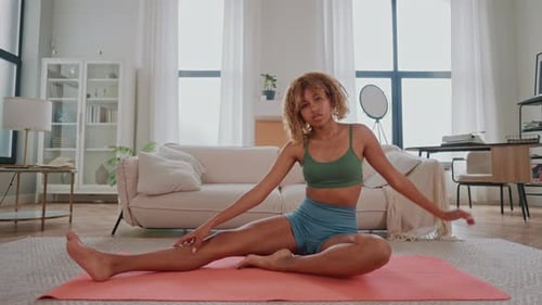 Woman Sitting on Yoga Mat in Living Room