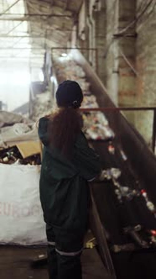A Young AfricanAmerican Woman Checks a Conveyor Belt at a Recycling Plant Pollution Control Zoomout
