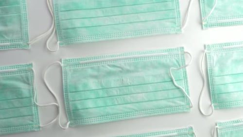 Many New Disposable Face Masks on White Surface