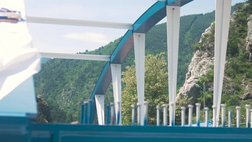 Bridge construction site with blue rigging equipment in a mountainous area under a bright sky
