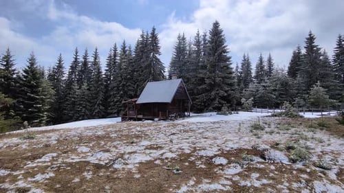 Wooden mountain house in the middle of the forest during winter time on a cloudy day.