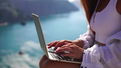 Woman Typing on Laptop with Ocean View
