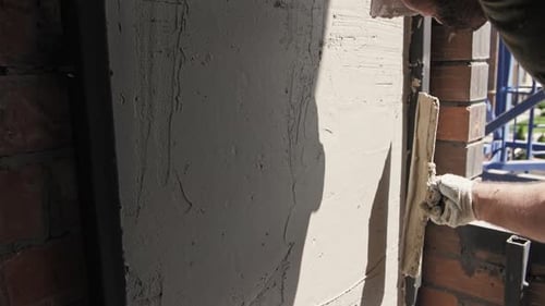 Construction Worker Applies Cement to an Outdoor Wall