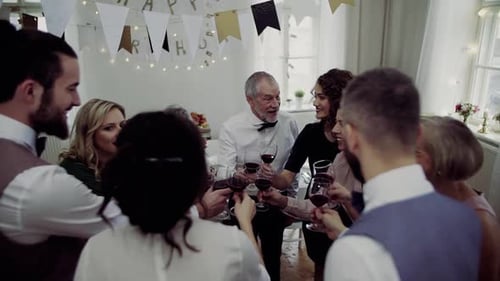 Group toasting red wine at birthday party indoors
