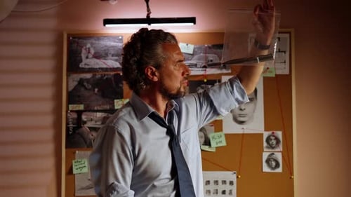 Closeup Detective's Office Middleaged Investigator in Shirt and Tie Sitting Desk Examining Evidence