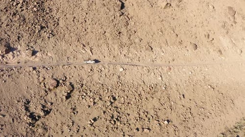 White pickup truck driving on dangerous cliff side gravel road. Person standing on the truck bed. Ae