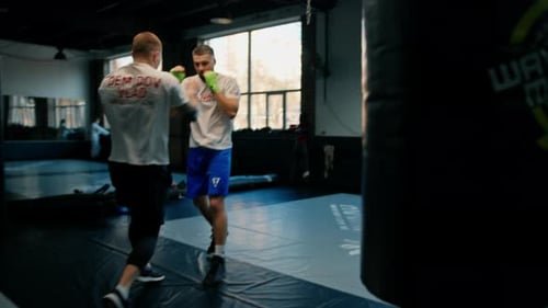 Sparringboxer üben im Fitnessstudio Schläge. Der Kampflehrer bringt Schläge für die Meisterschaft
bei