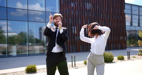 Caucasian Young Man and Woman in Formal Wear Dancing Happily Together Near Modern Office Center