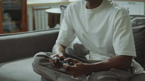Man Plays Video Game on Couch at Home