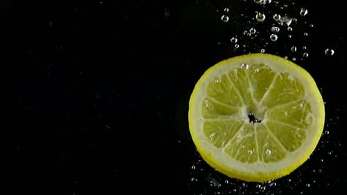 Lemon Slices Falling into Water on Black Background