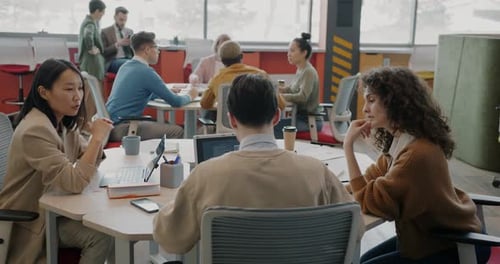 Multiethnic Group of Businesspeople are Working in Light Coworking Space Sitting at Desks