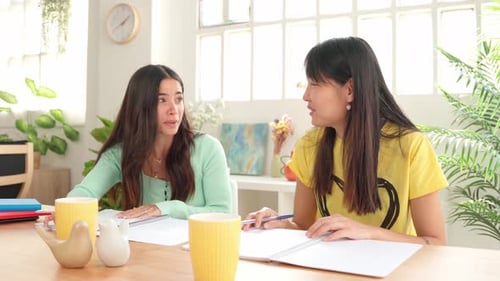 Two Young Adults Talking at a Table Indoors