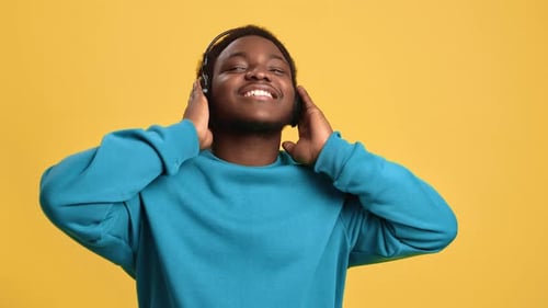 Happy Afro Man Dancing Listening Favorite Music in Headphones Posing Isolated Orange Studio Closeup