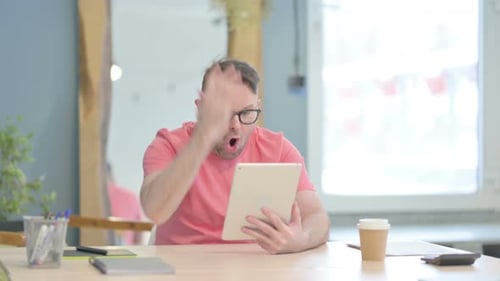 Man Frustrated Using Tablet at Office Desk