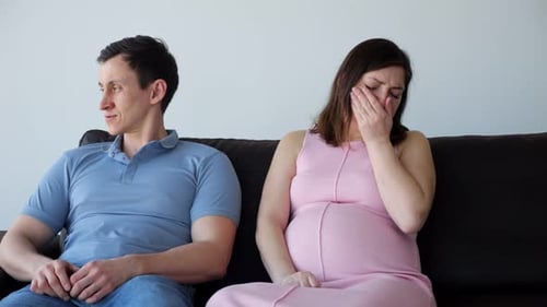 Upset Pregnant Woman Sitting on Couch with Man