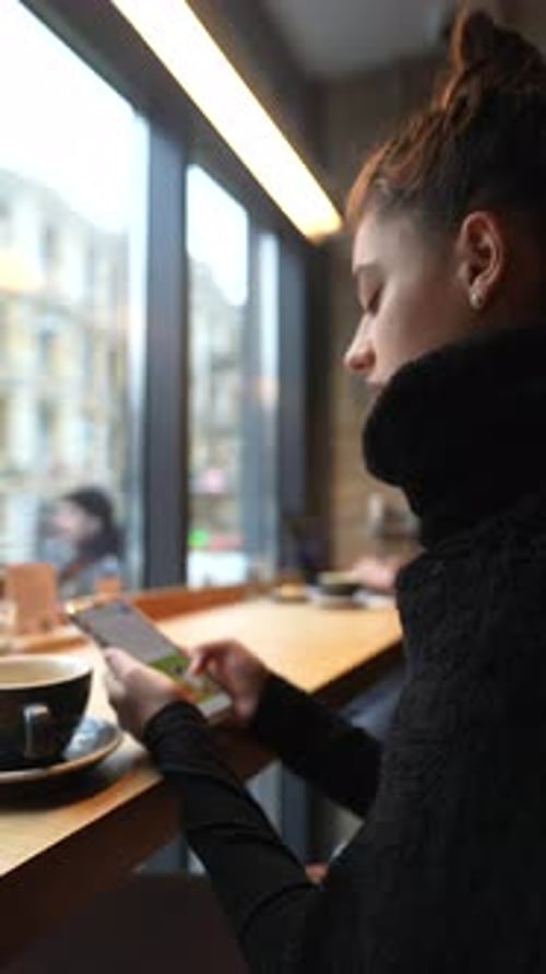 Close Up Portrait of Young Beautiful Girl Drinking Coffee with Smartphone in Hands