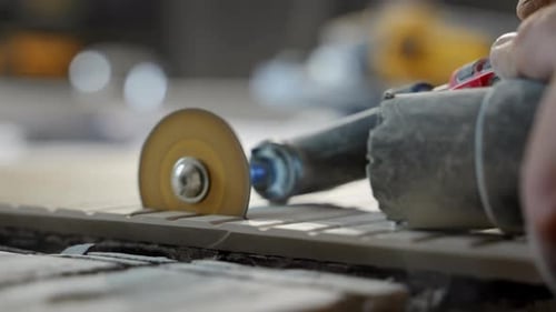 Worker is Cutting Ceramic Tile with an Small Electric Angle Grinder Workshop or Renovation Site