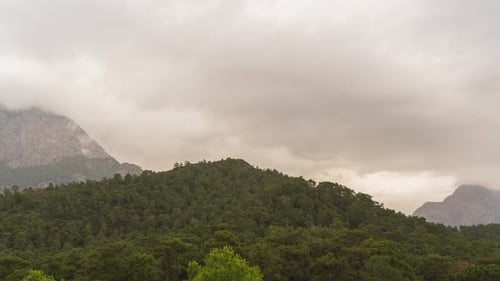 Zeitraffer von Regenwolken, die durch Berge und Wälder in die Ferne fliegen. Variabler Niederschlag.