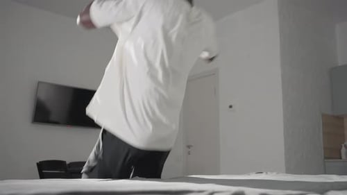 Man Jumps and Lays on Bed in Apartment