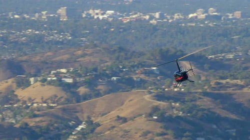 Helicopter flies over Los Angeles California with san gabriel mountains peaks in view