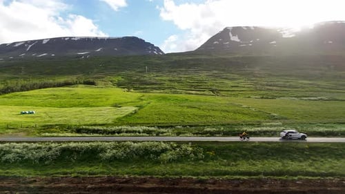 Aerial drone view of two cyclists riding on Route 82 along the Eyjafjörður fjord in Iceland,