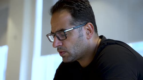 A person sits indoors, curiously looking at their mobile phone.