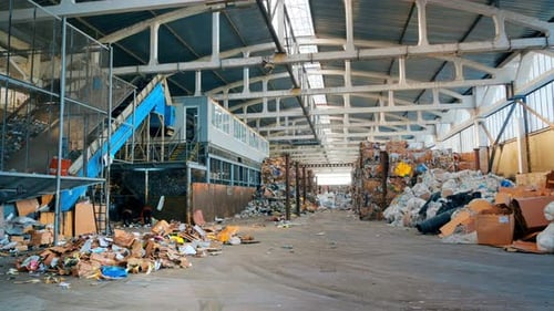 View of interior of a waste sorting plant. Garbage everywhere, special tools, workers