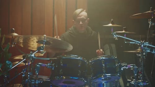 Musician Plays Drums in a Dimly Lit Studio During a Recording Session