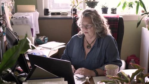 Confident senior woman works independently on laptop in her home office