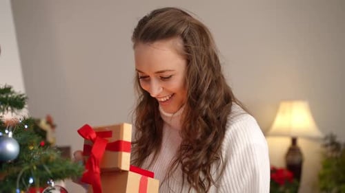 Excited Woman Opens Gift near Christmas Tree