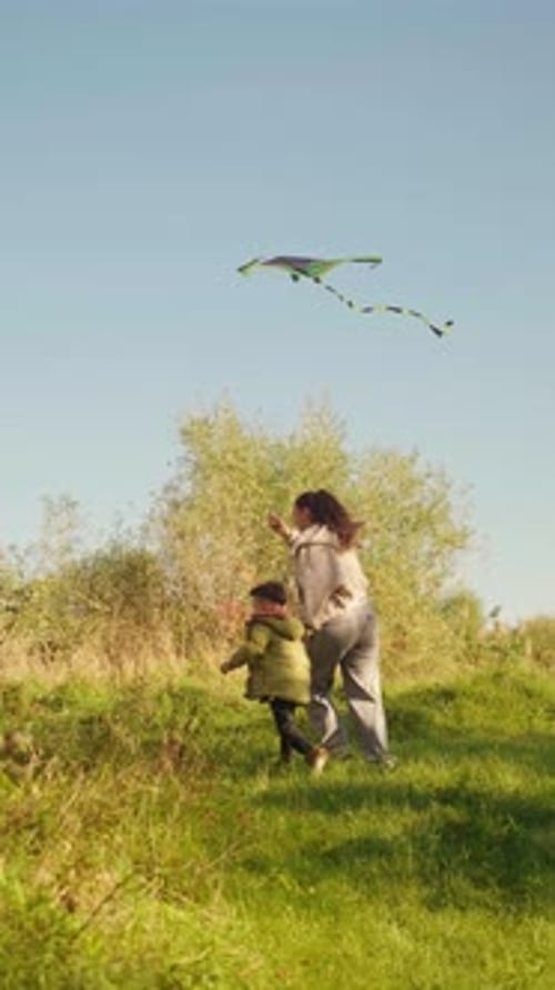 Child and Woman Flying Kite in Rural Field