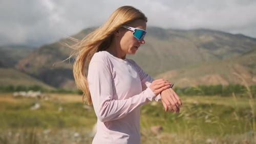 Athlete Adjusts the Timer and Starts Her Run Maintaining Fitness in the Wind